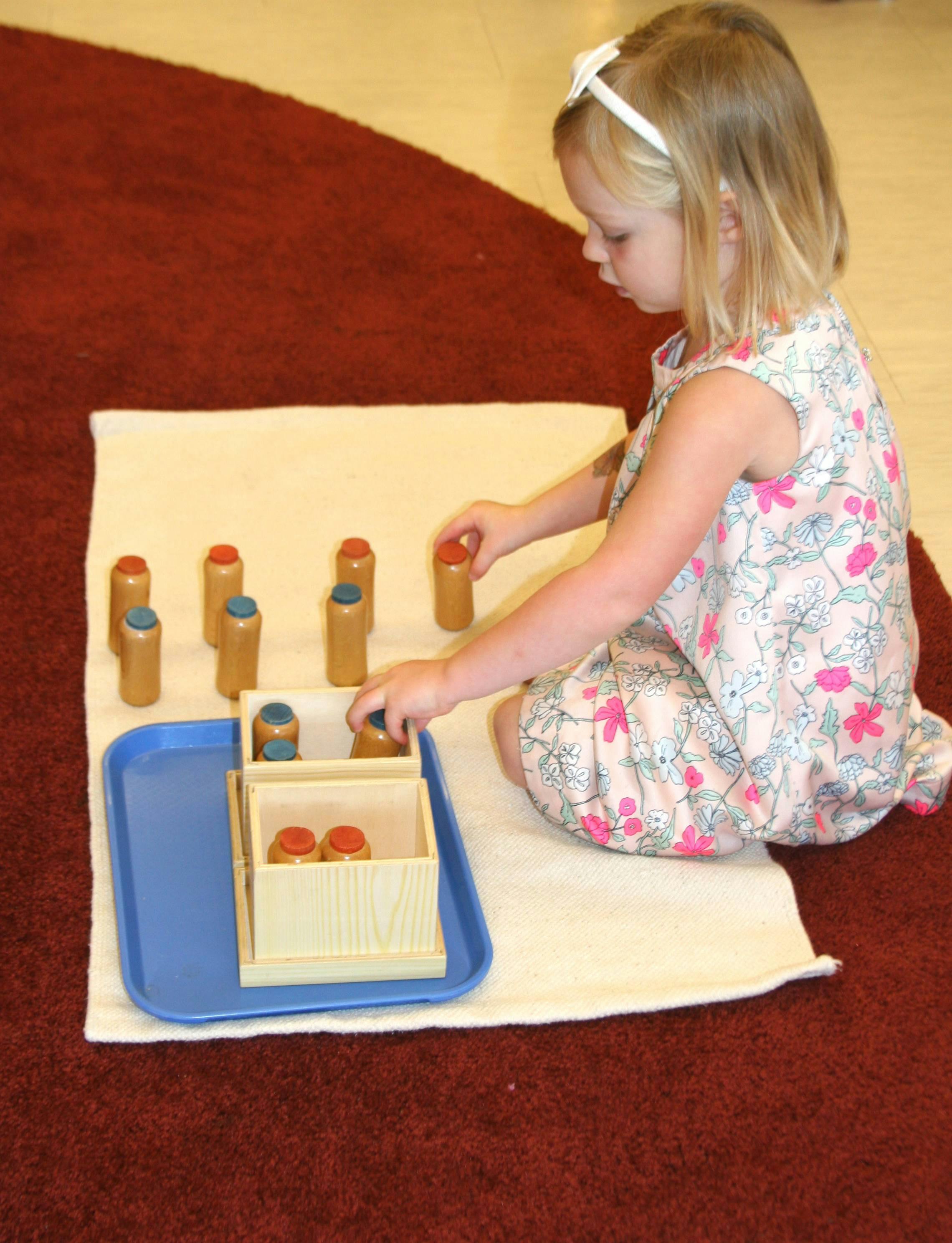 Child playing with wooden cylinders on a mat