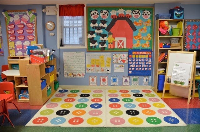 Classroom with colorful rug, bulletin boards, and small furniture