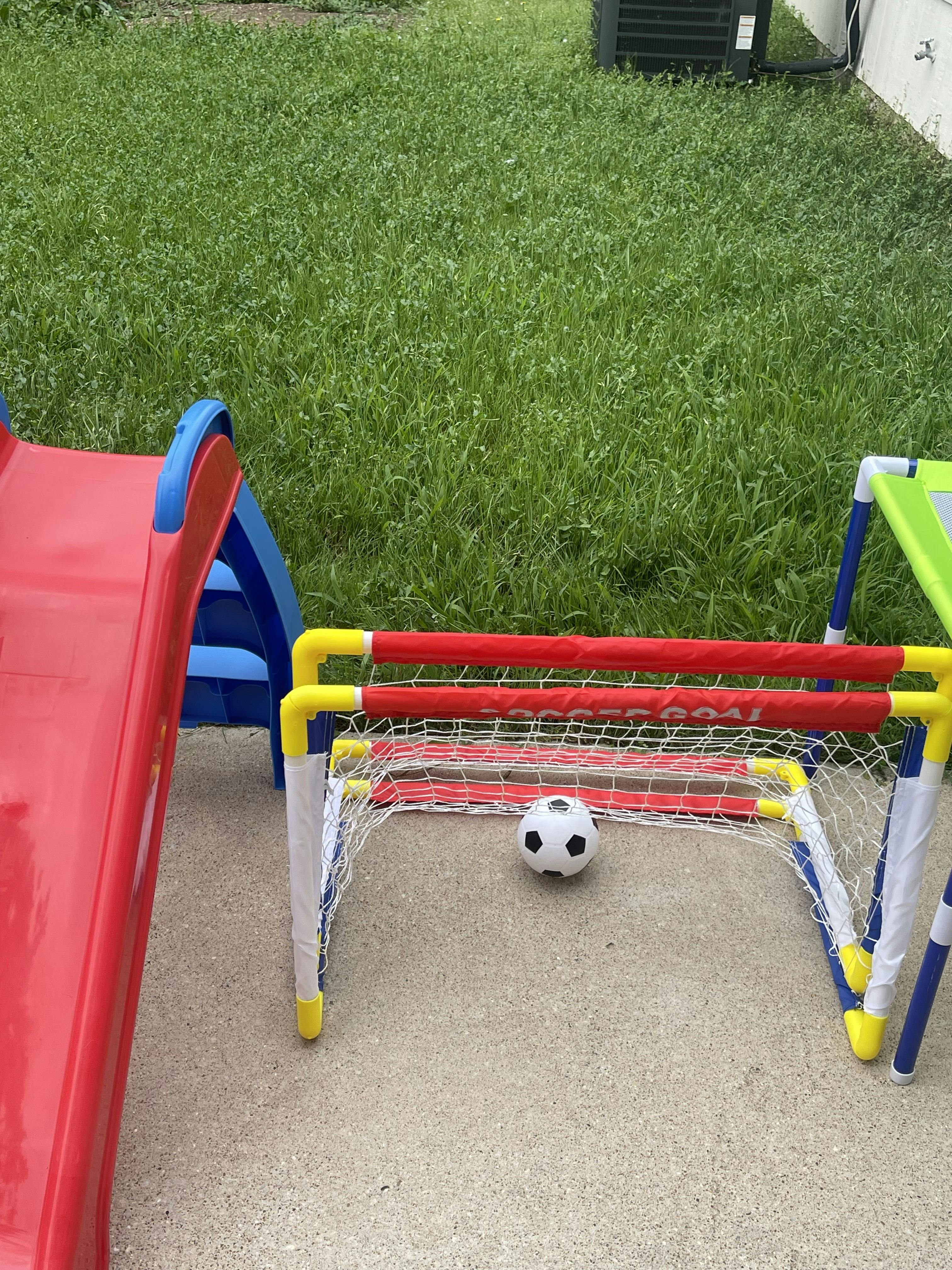 Soccer ball in front of a small soccer goal next to a red slide