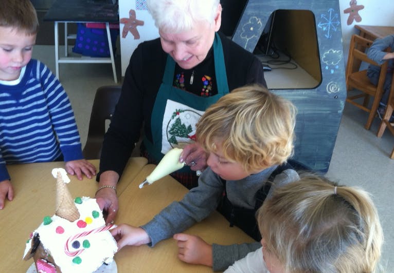 Adult and children decorating a gingerbread house