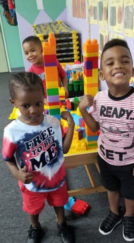Three children standing near a table with colorful building blocks