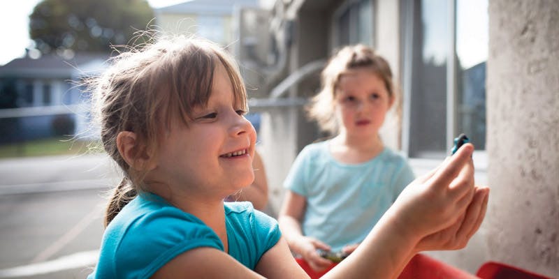 Child holding a small object, another child in the background