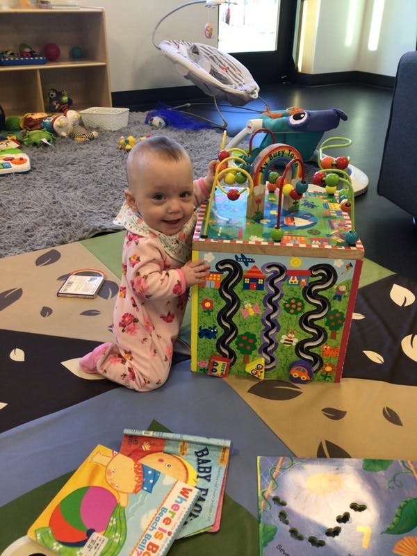 Child kneeling next to a large activity cube toy
