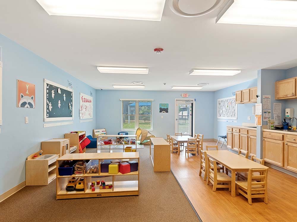 Classroom with small tables, chairs, and play stations