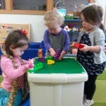 Three children playing with blocks at a table