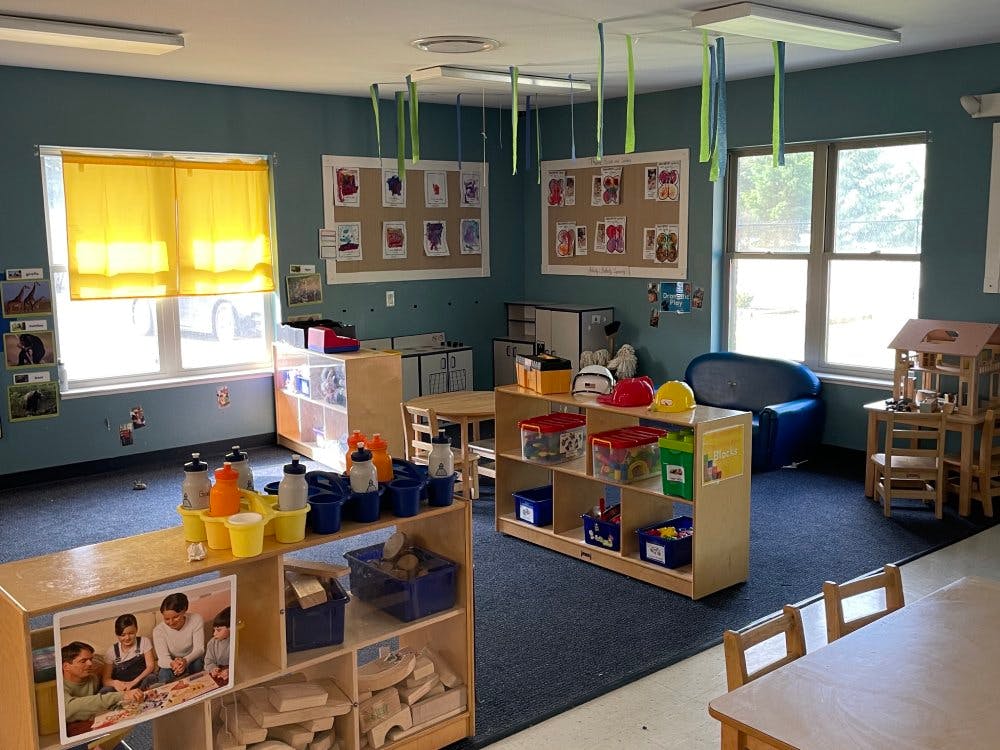 Classroom with tables, chairs, shelving units, and artwork on the walls