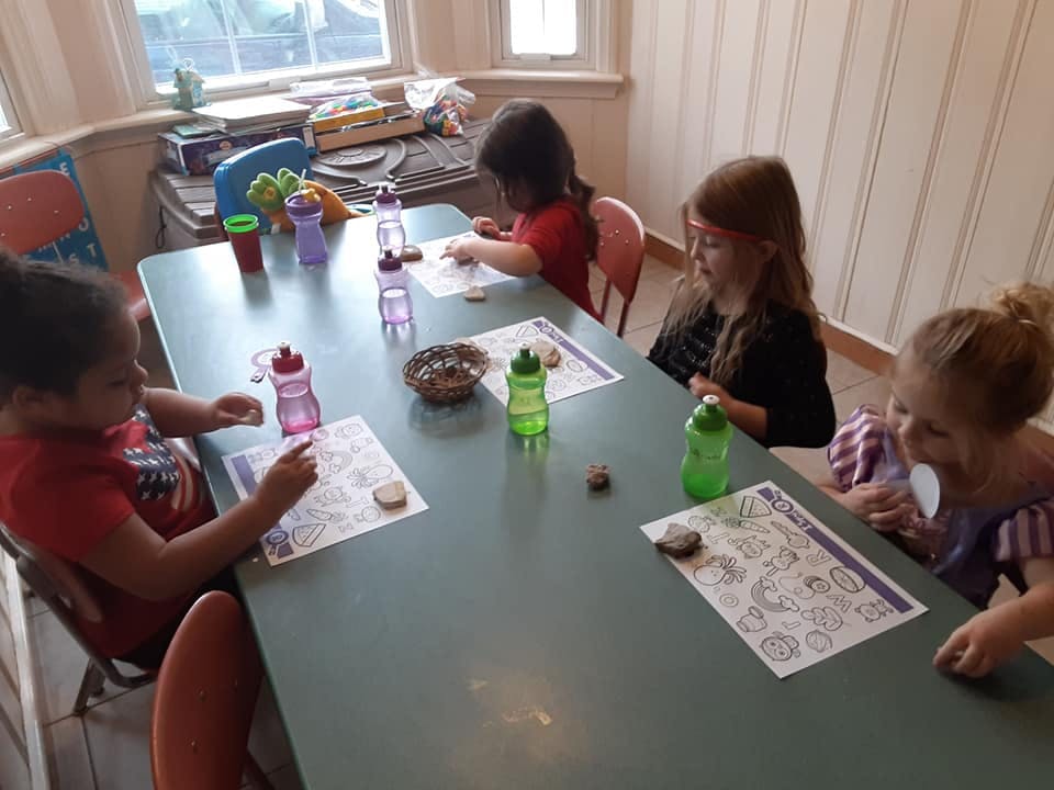 Four children sitting at a table with papers and water bottles