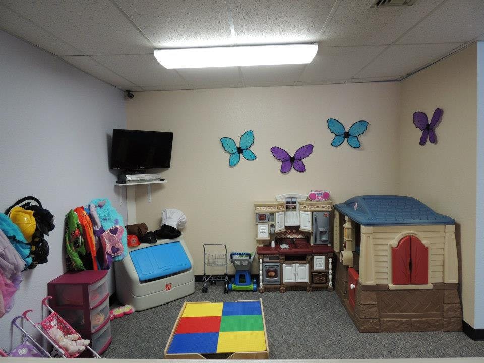 Playroom with a playhouse, toy kitchen, and colorful butterfly wall decorations