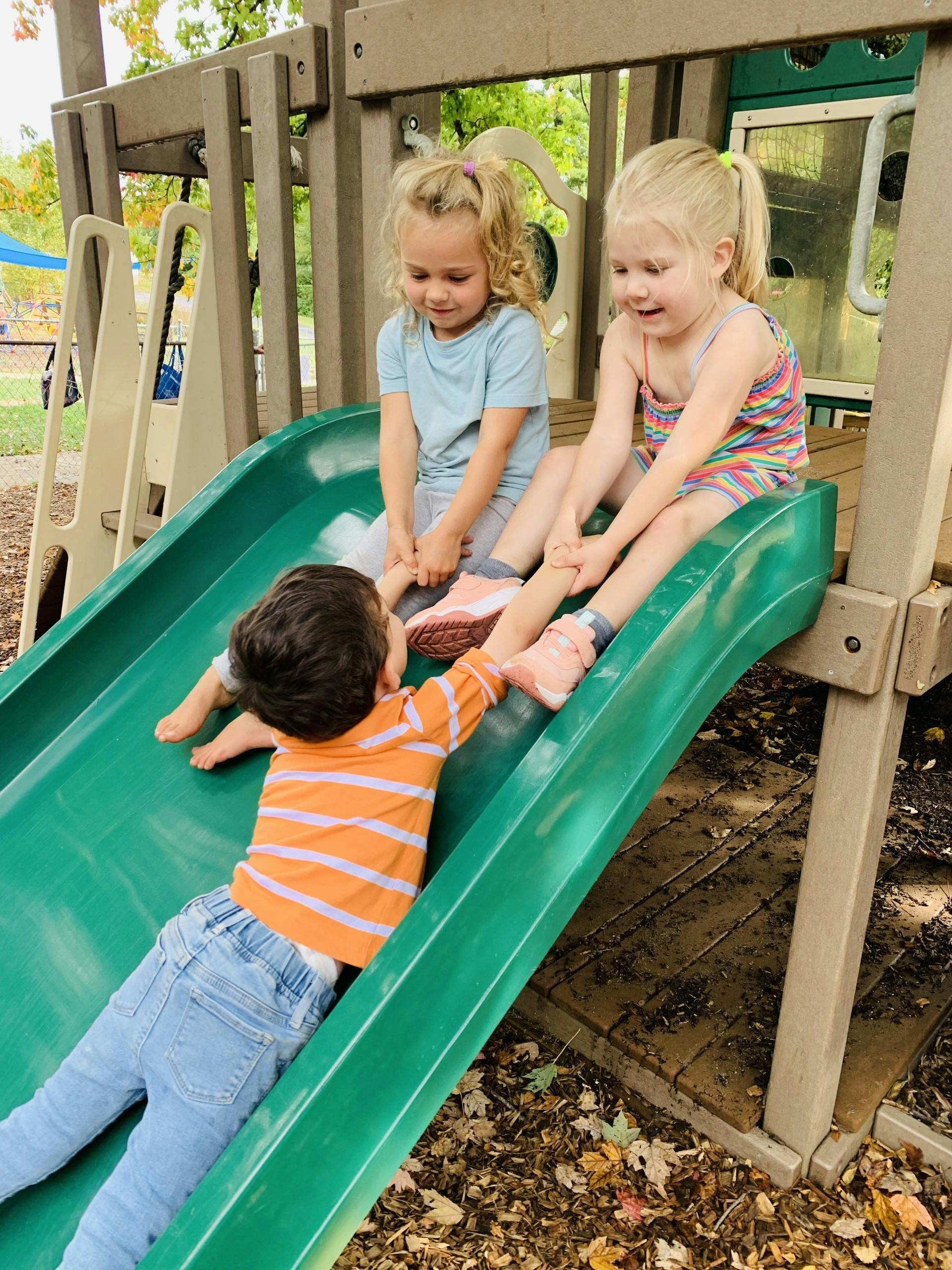 Three children playing together on a playground slide