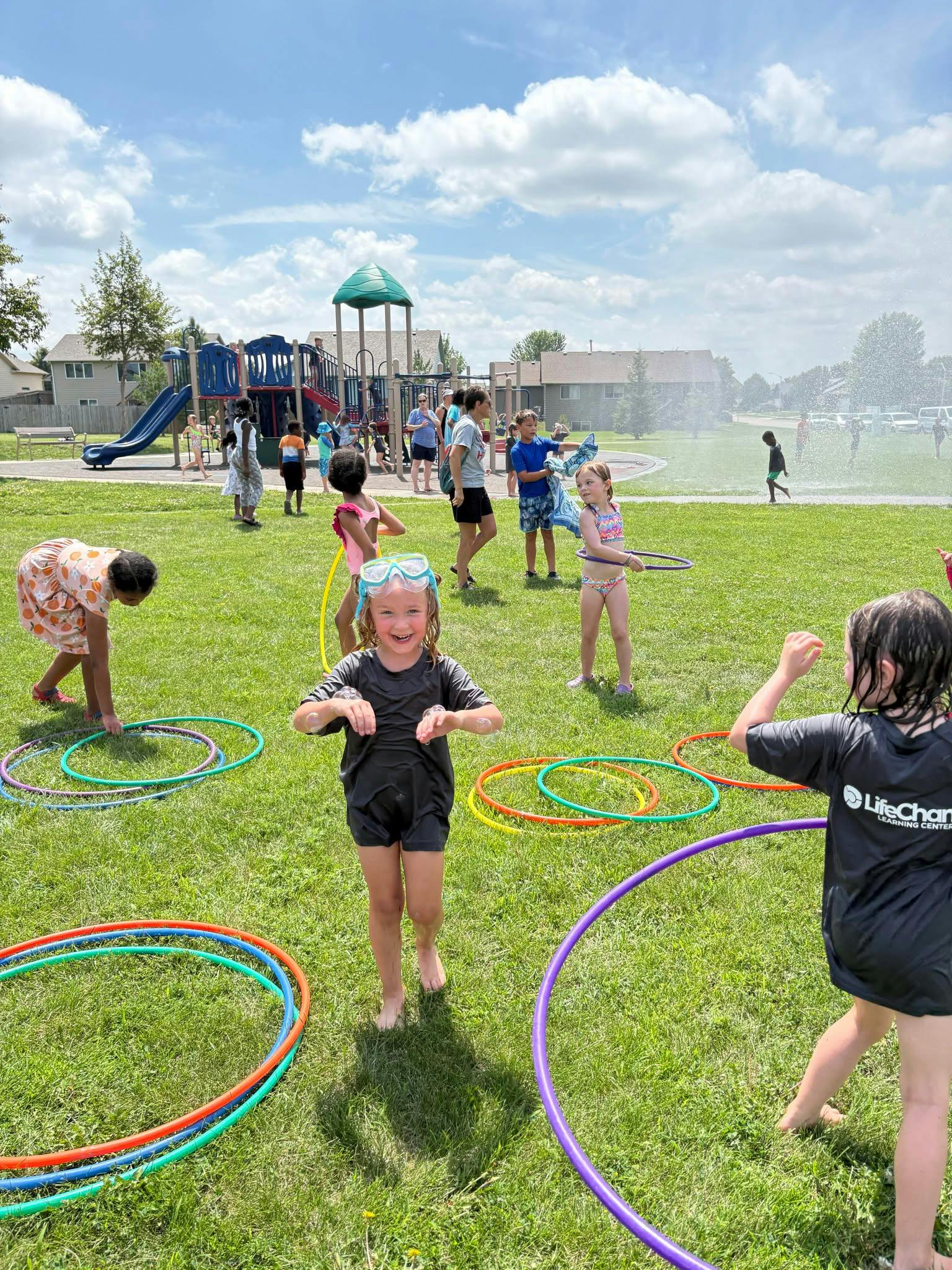 Children playing with hula hoops on a grassy field