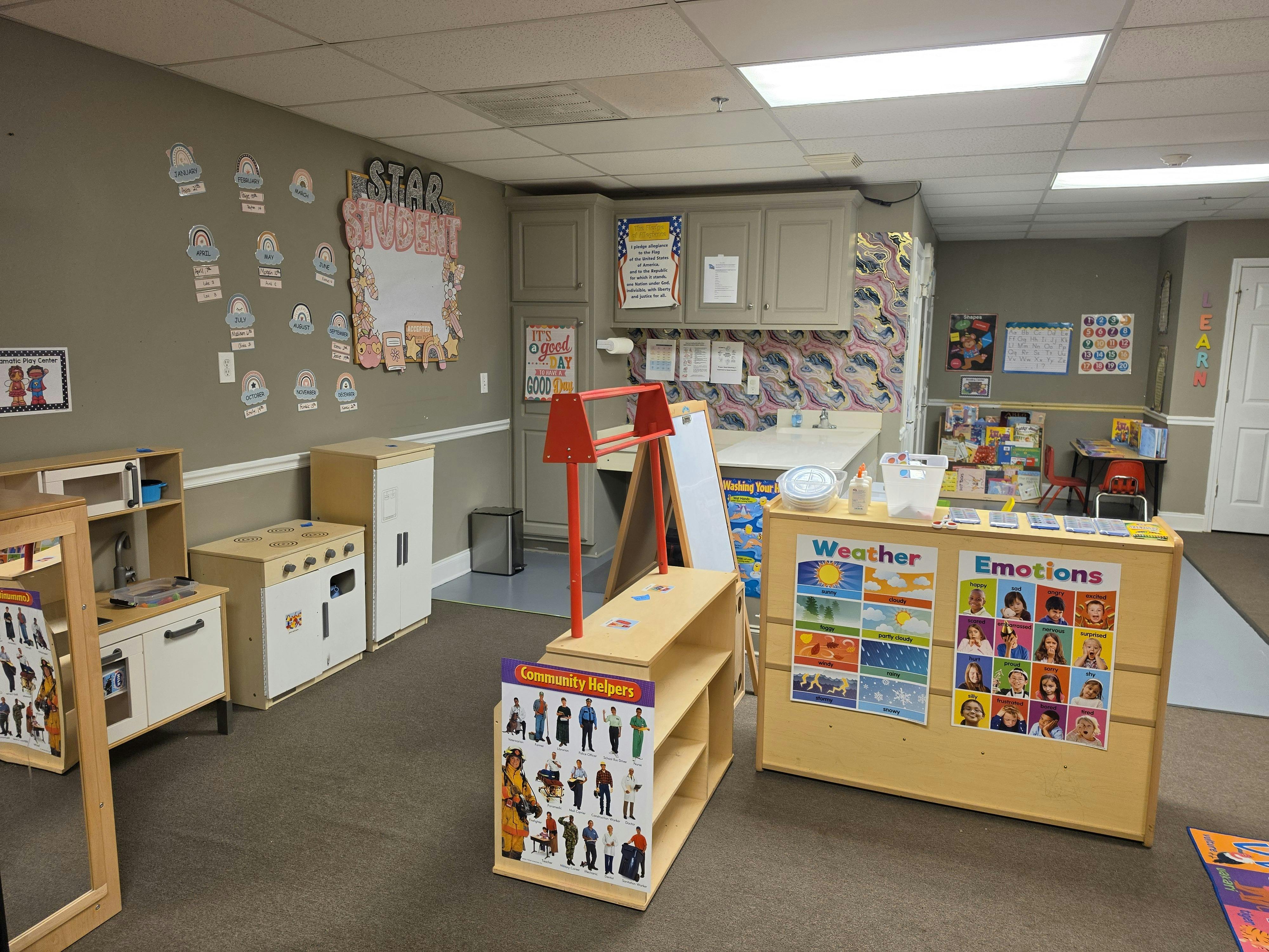 Classroom with play kitchen, shelves of books and teaching aids