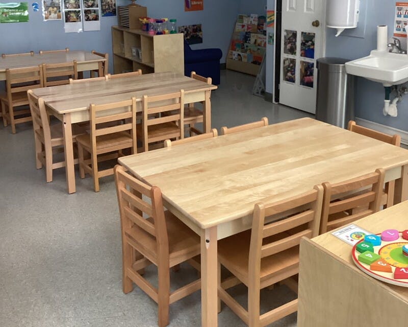 Classroom with multiple wooden tables and chairs set up