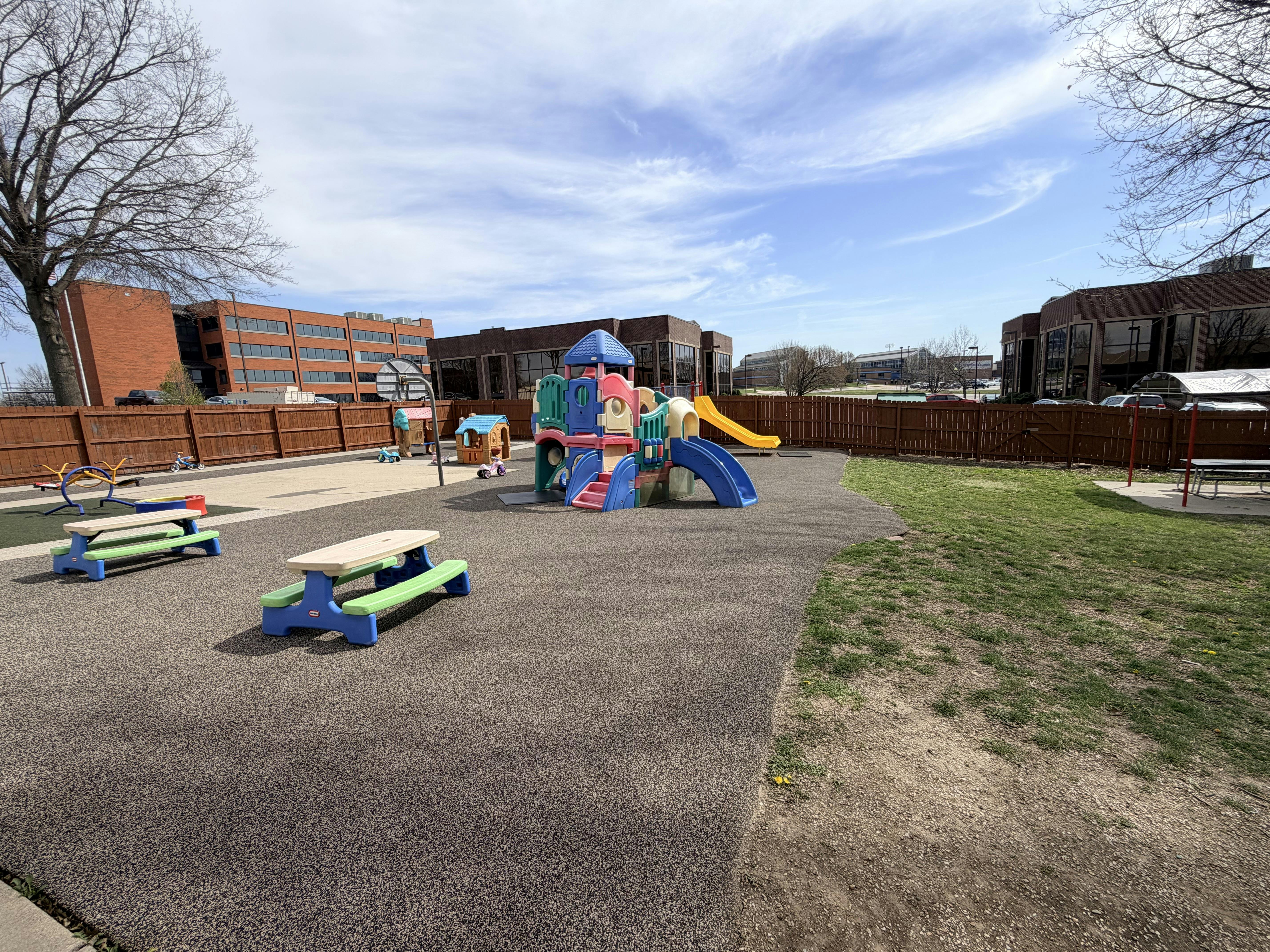 Outdoor playground with colorful play structures and picnic tables on a sunny day
