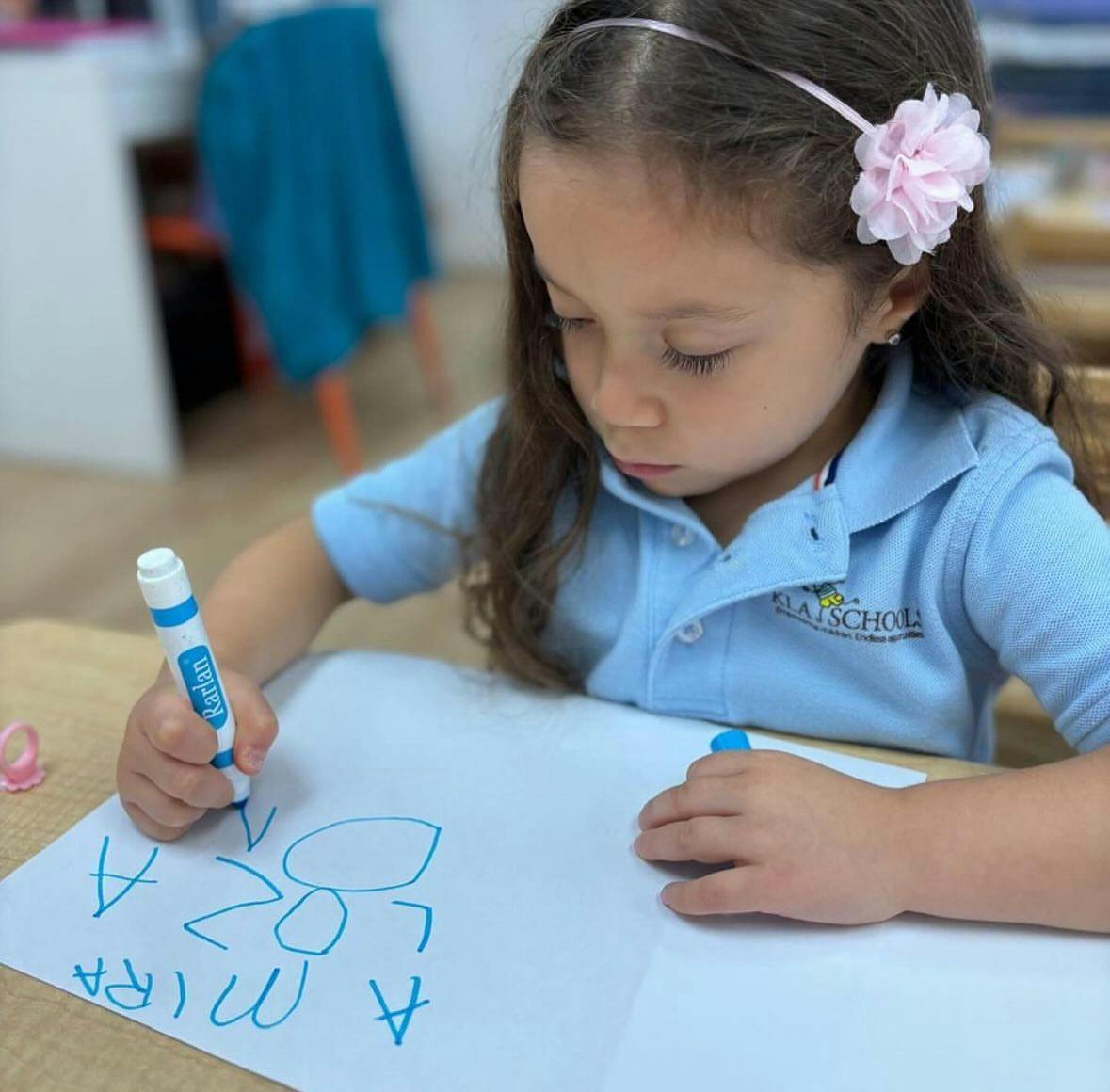 Child drawing on paper with a blue marker