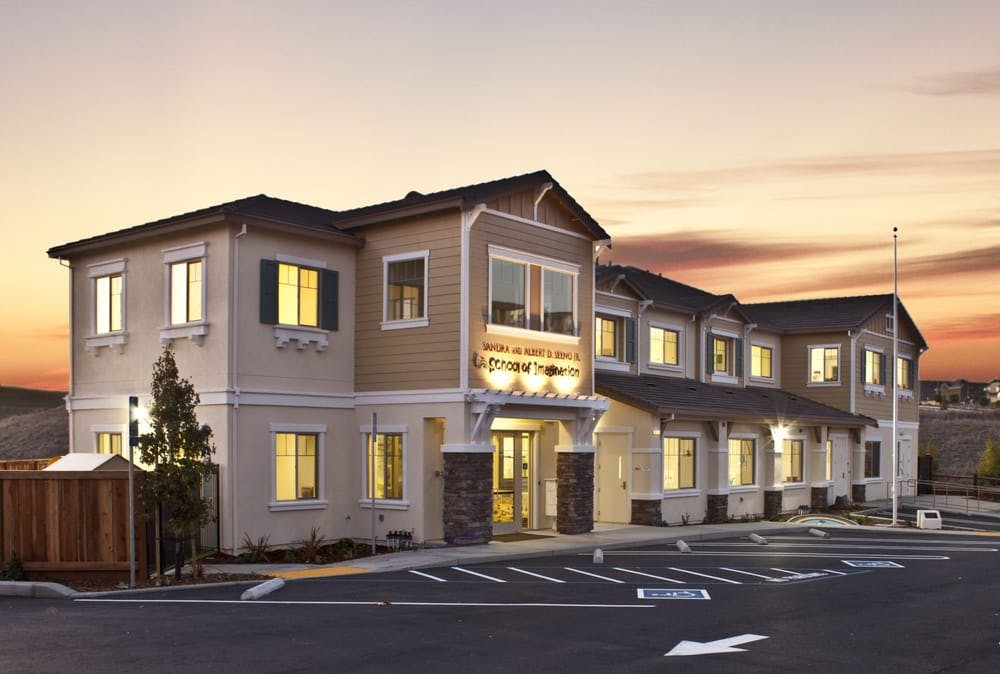 Exterior of a large building with a parking lot at sunset