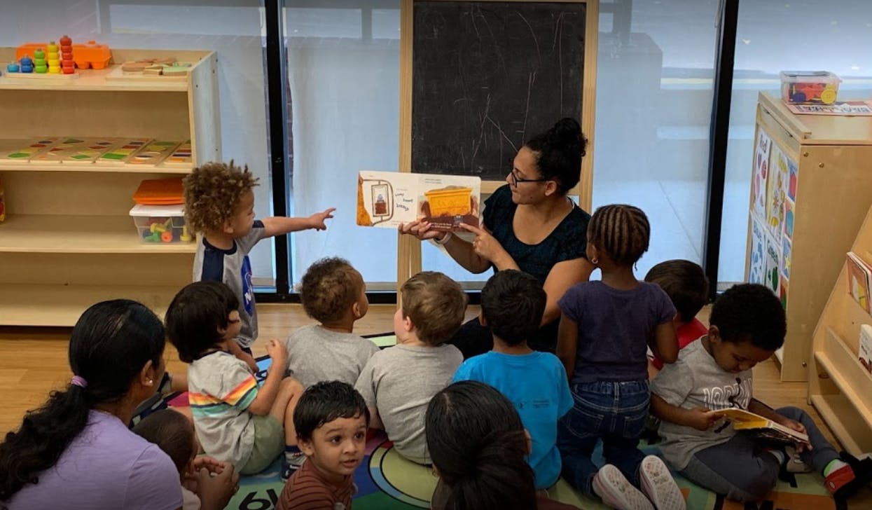 Person reading a book to a group of children in a classroom