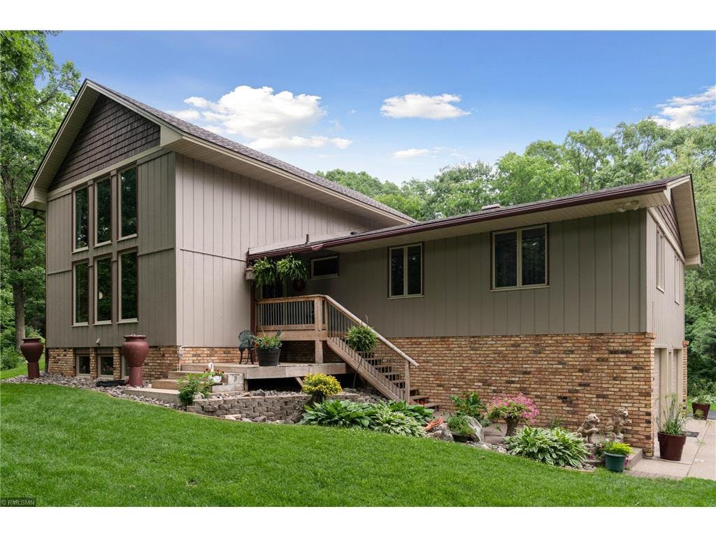 House exterior with multiple windows, brick foundation, and outdoor stairs
