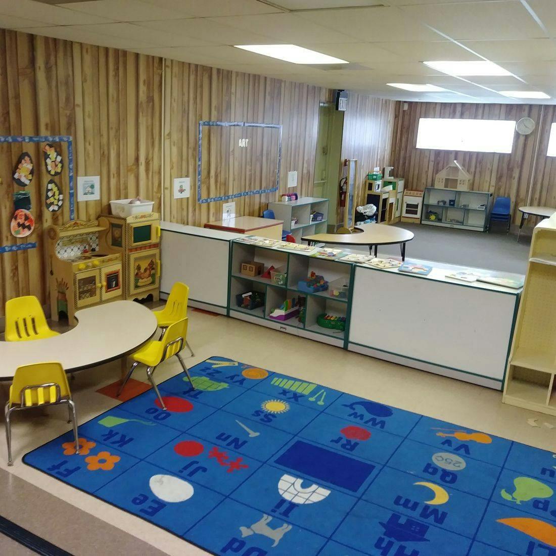 Empty classroom with a blue alphabet rug and small tables
