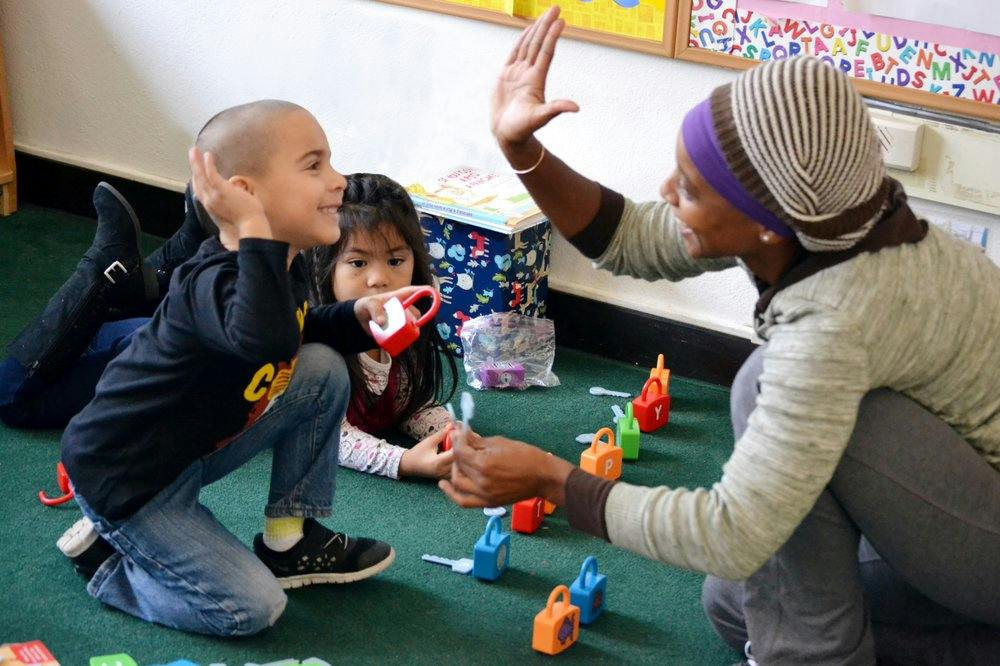 Adult and child playing with toys on the floor