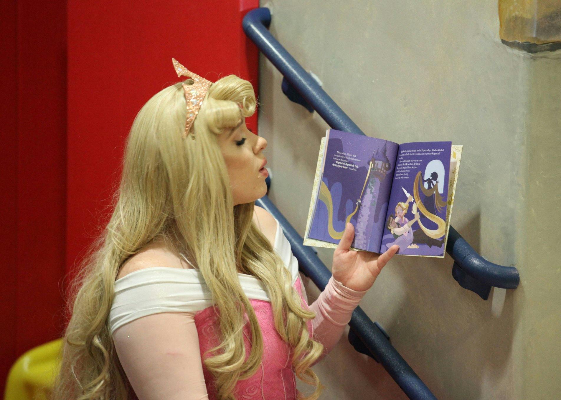 Person with long blonde hair reading an open book with illustrations