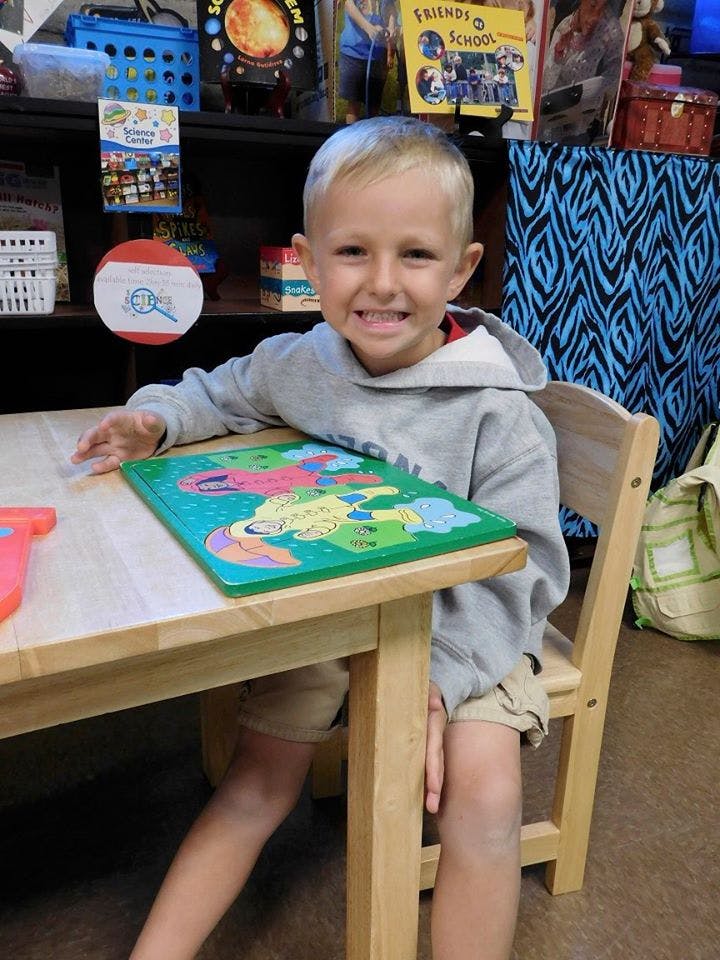 Child sitting at a table with a puzzle
