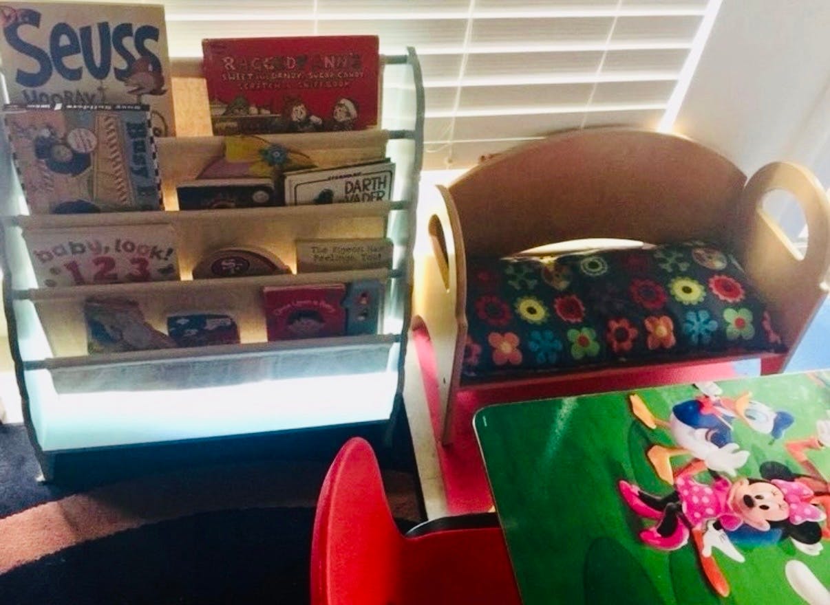 Child's book rack with various books and a small chair next to it