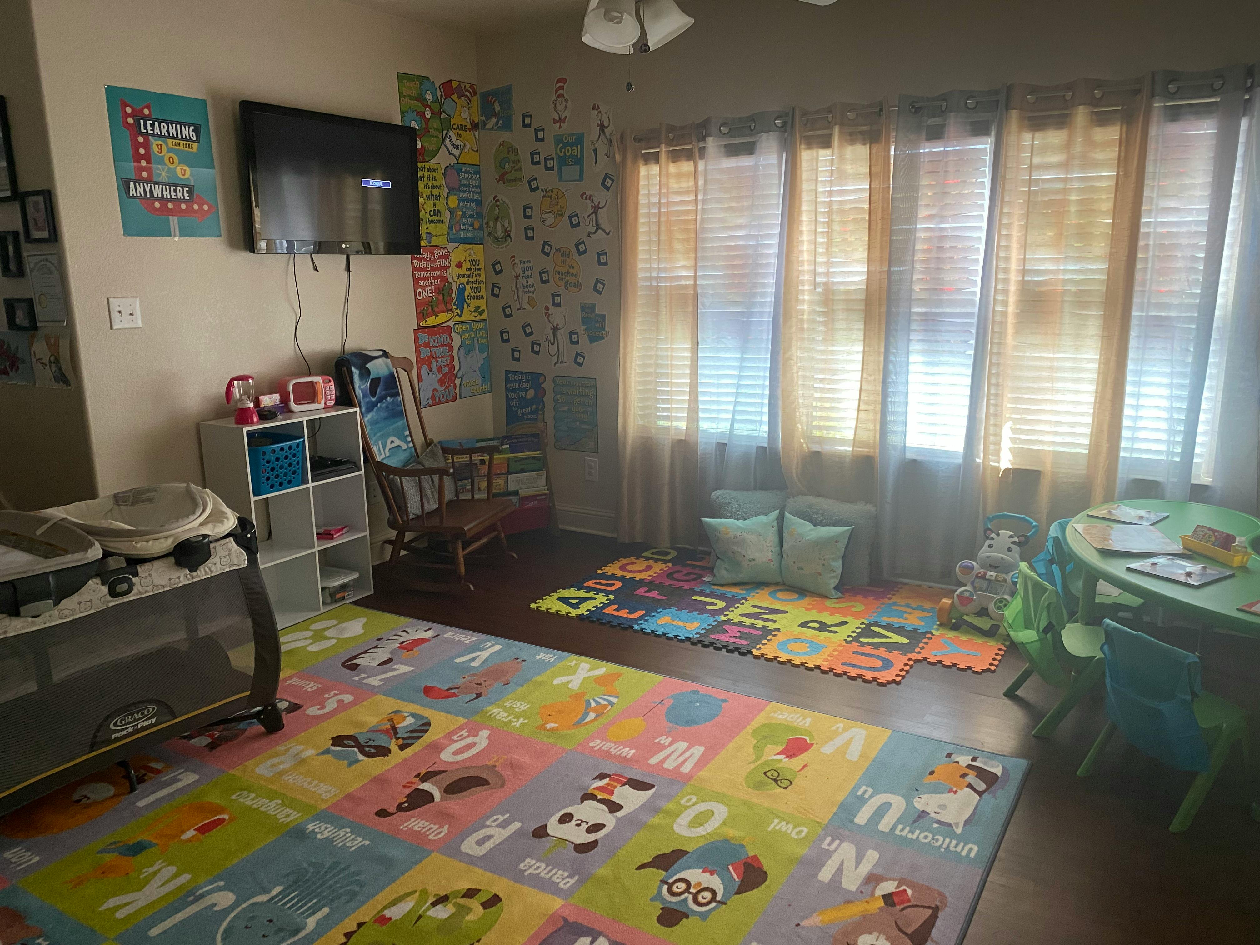 Playroom with colorful alphabet mats, a crib, and a small table with chairs
