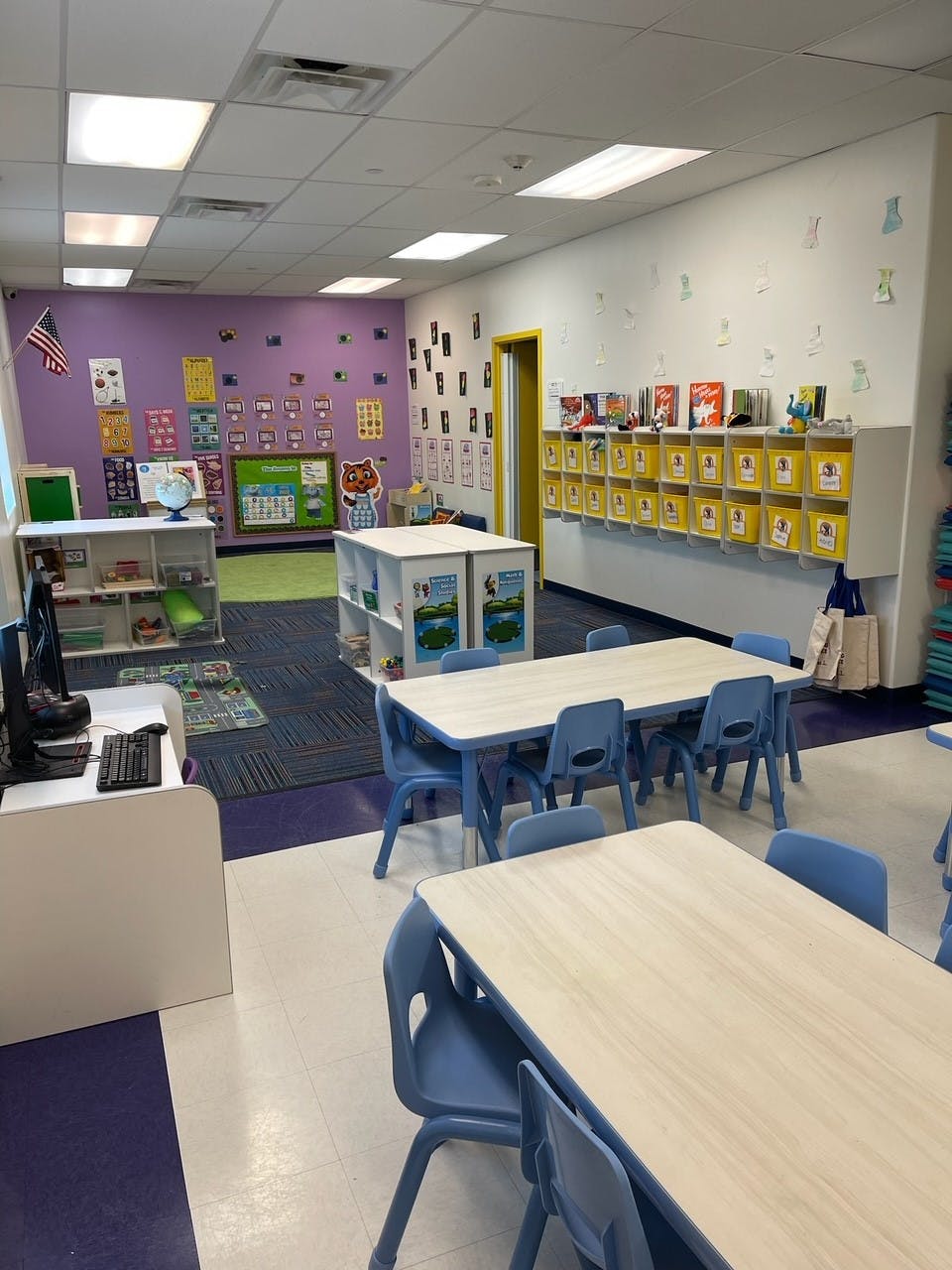 Classroom with small tables and chairs, storage cubbies, and wall decorations