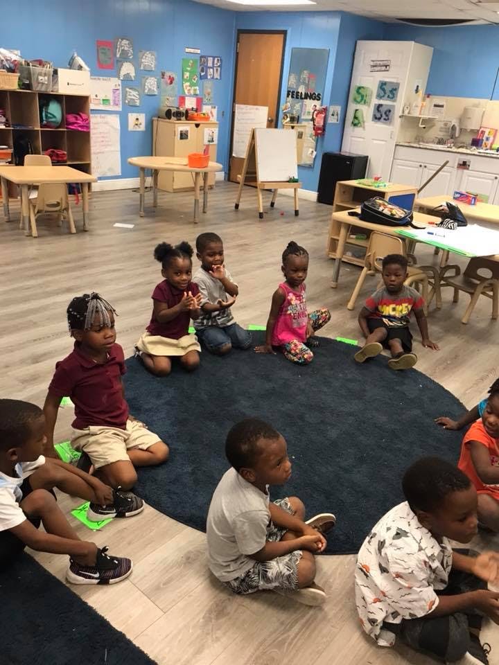 Children sitting on a rug in a classroom