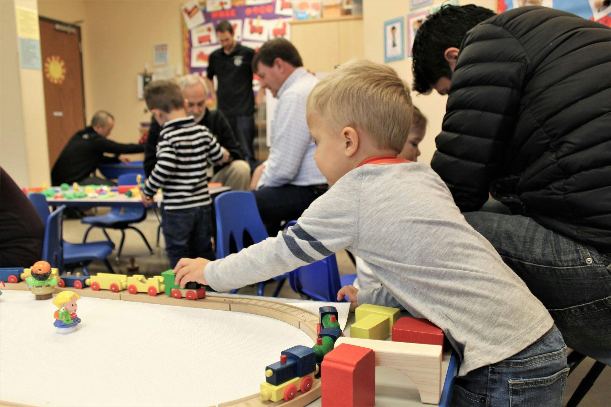 Child playing with a toy train set on a table
