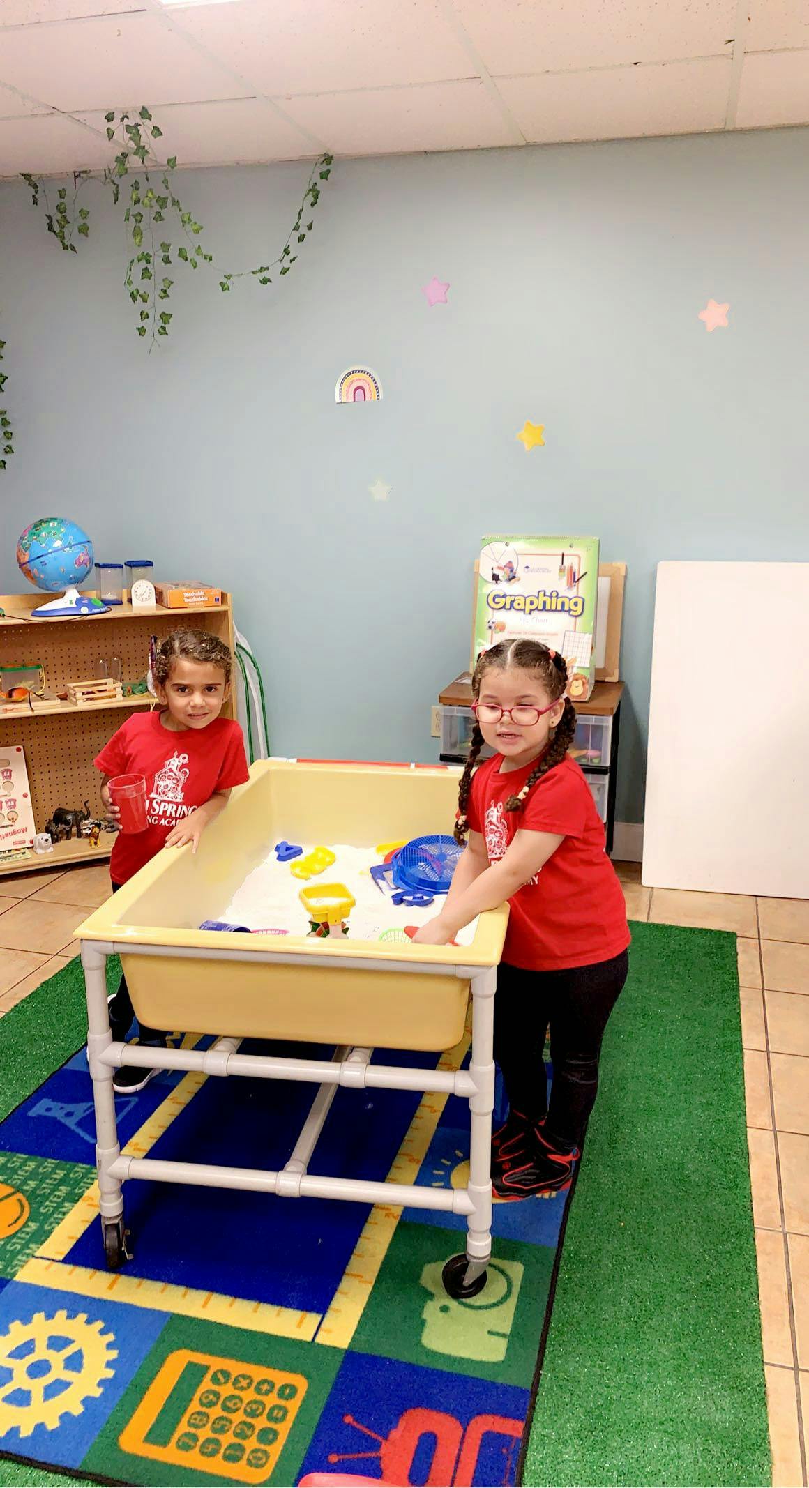 Two children playing at a sensory table in a classroom