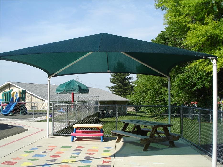 Shade structure over a picnic table and children's bench on a patio