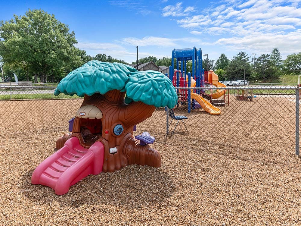 Playground with a tree-themed playhouse and larger climbing structure
