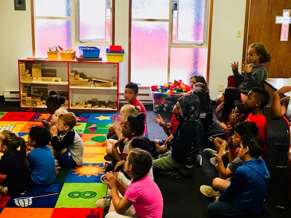 Children sitting on a colorful rug in a classroom