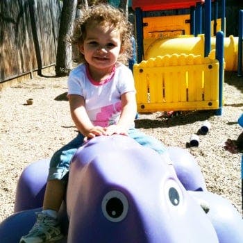 Child on a purple spring rider toy on a playground