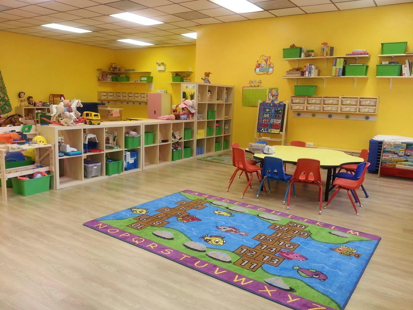 Playroom with yellow walls, cubbies, a rug, and a table with chairs