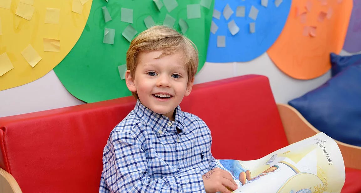Child in a plaid shirt sitting on a red couch