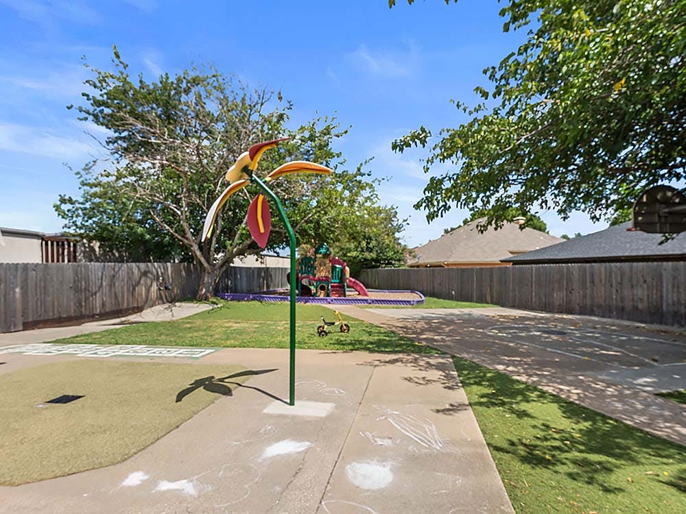 Playground with a slide, sandpit, and a flower-shaped sprinkler