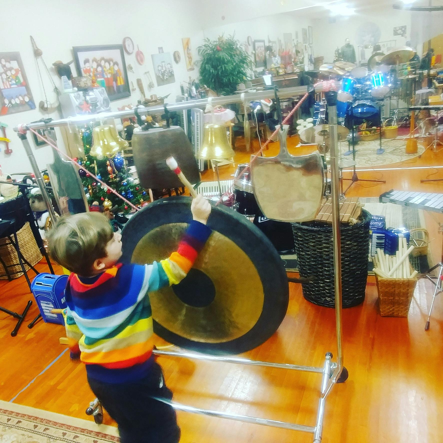 Child playing a large gong with a mallet