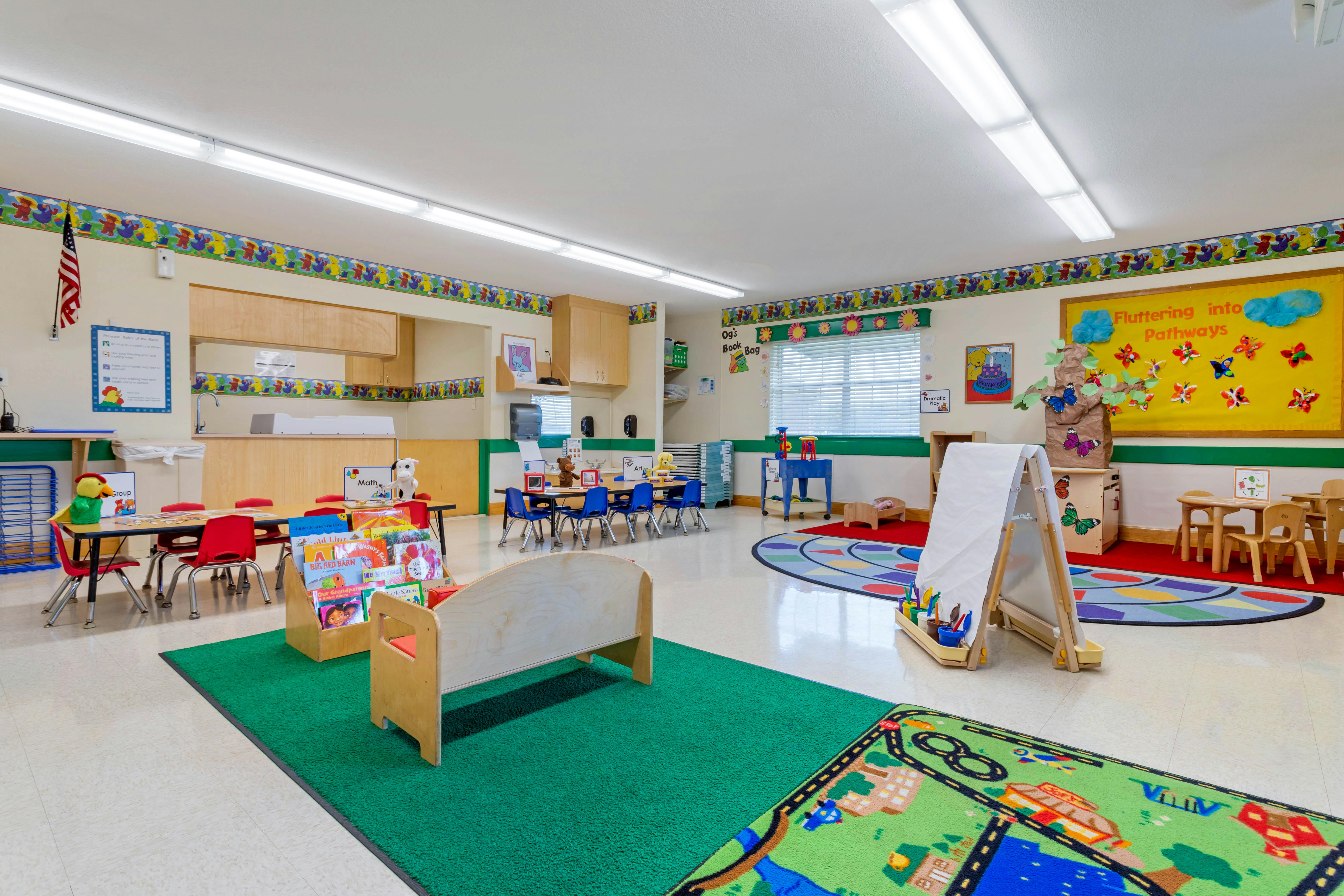 Colorful empty classroom with small tables, chairs, and learning materials