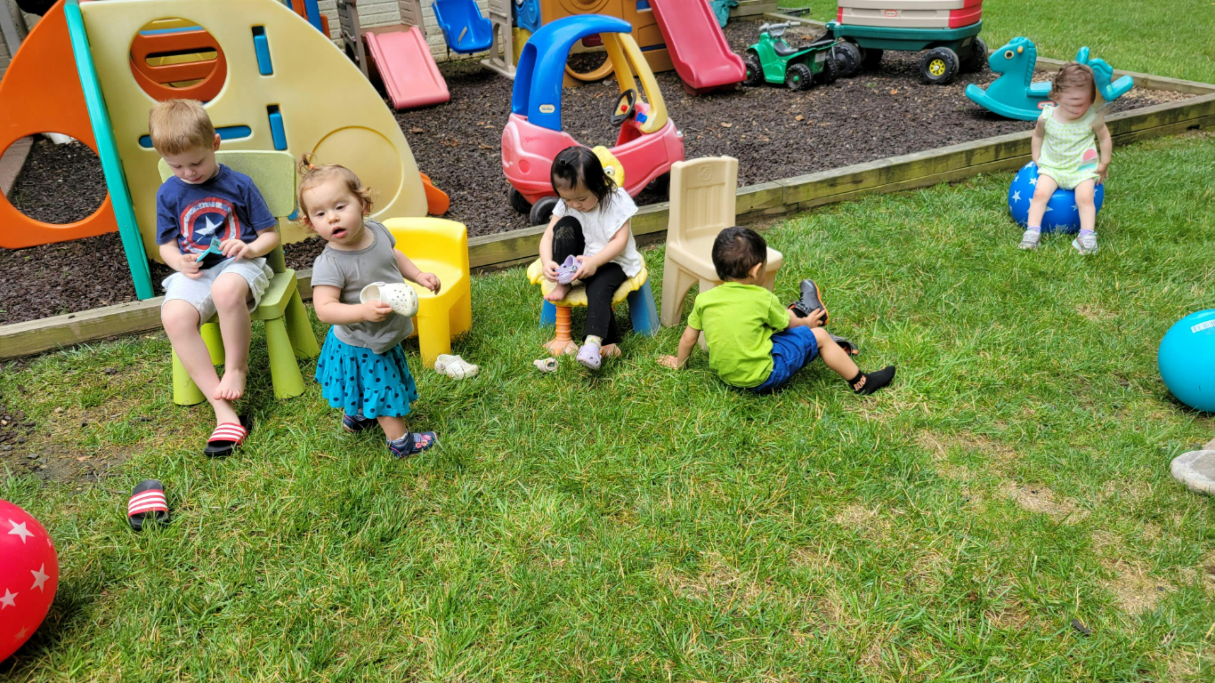 Children playing on a grassy playground with colorful equipment