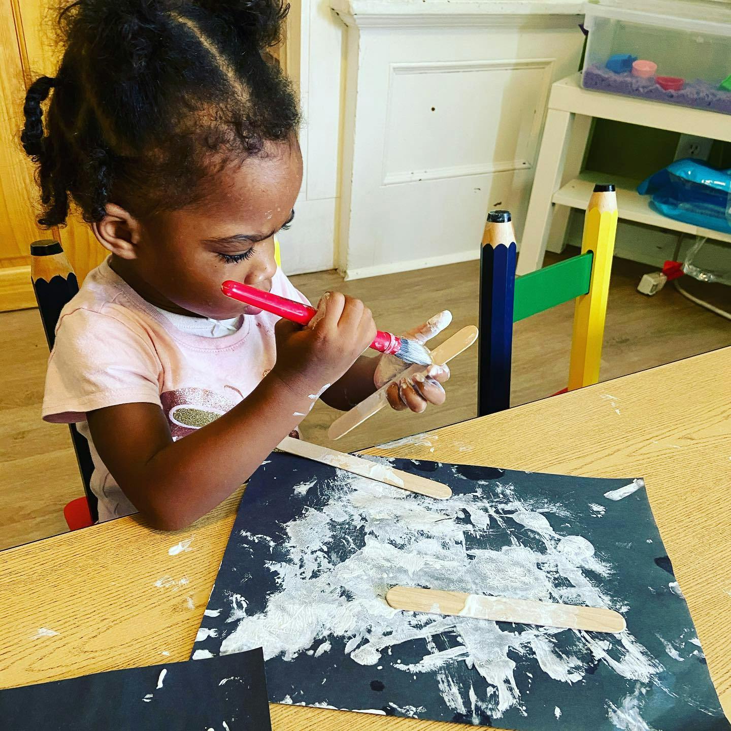 Child painting craft sticks with a brush