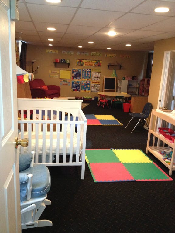 Nursery room with a white crib, colorful playmats, and a small table with chairs