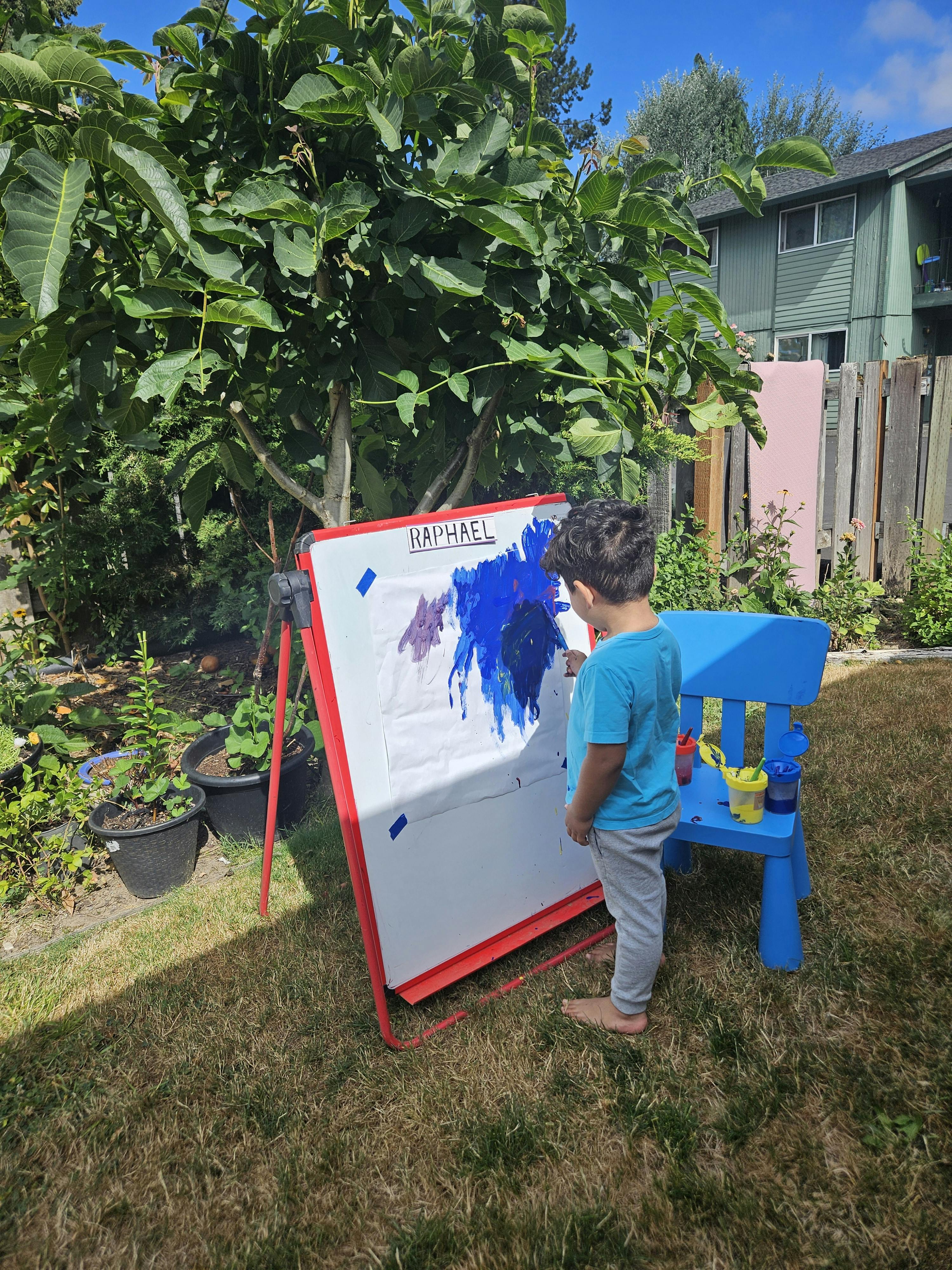 Child painting on an easel outdoors