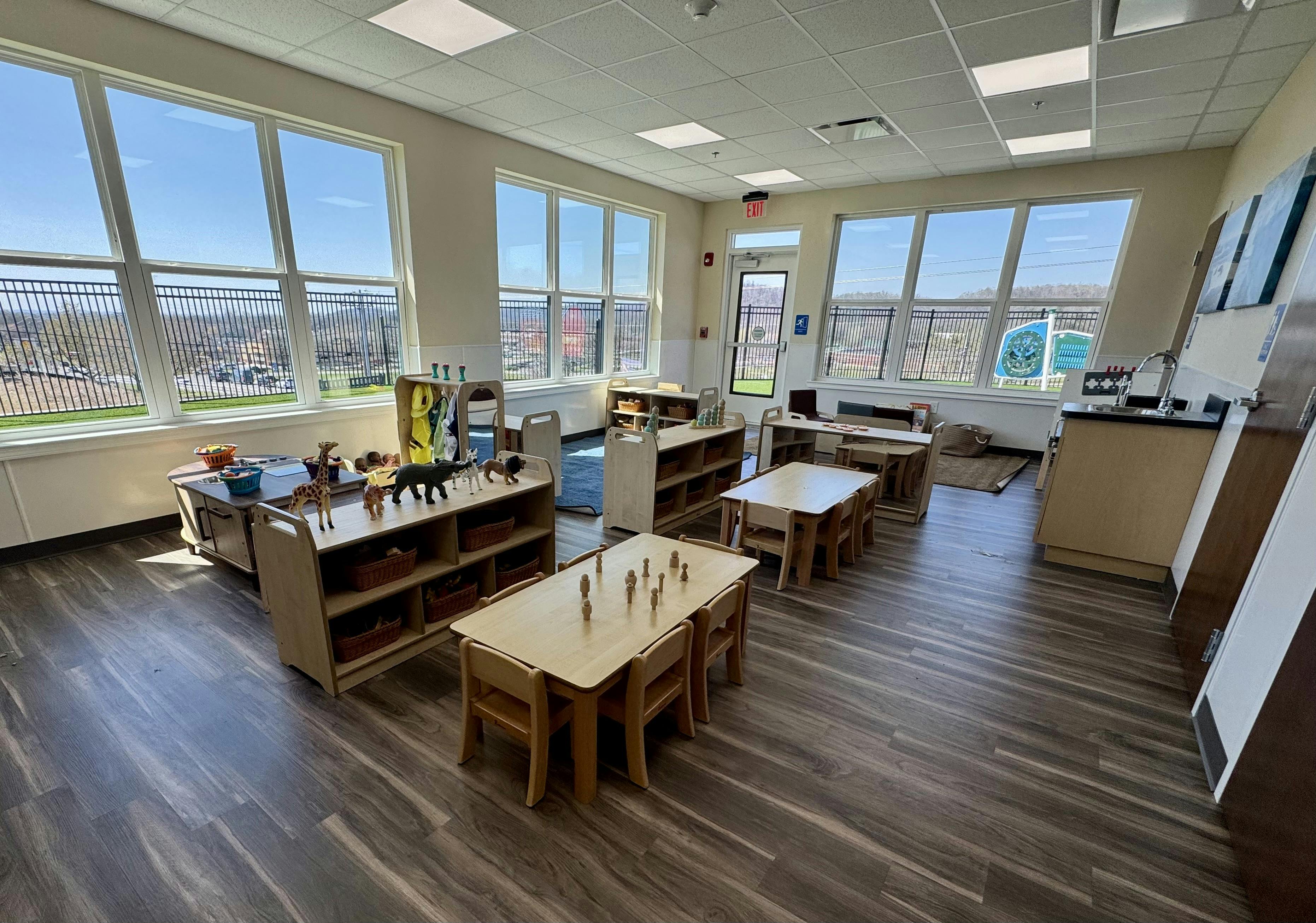 Childcare classroom with small tables and wooden toy storage shelves