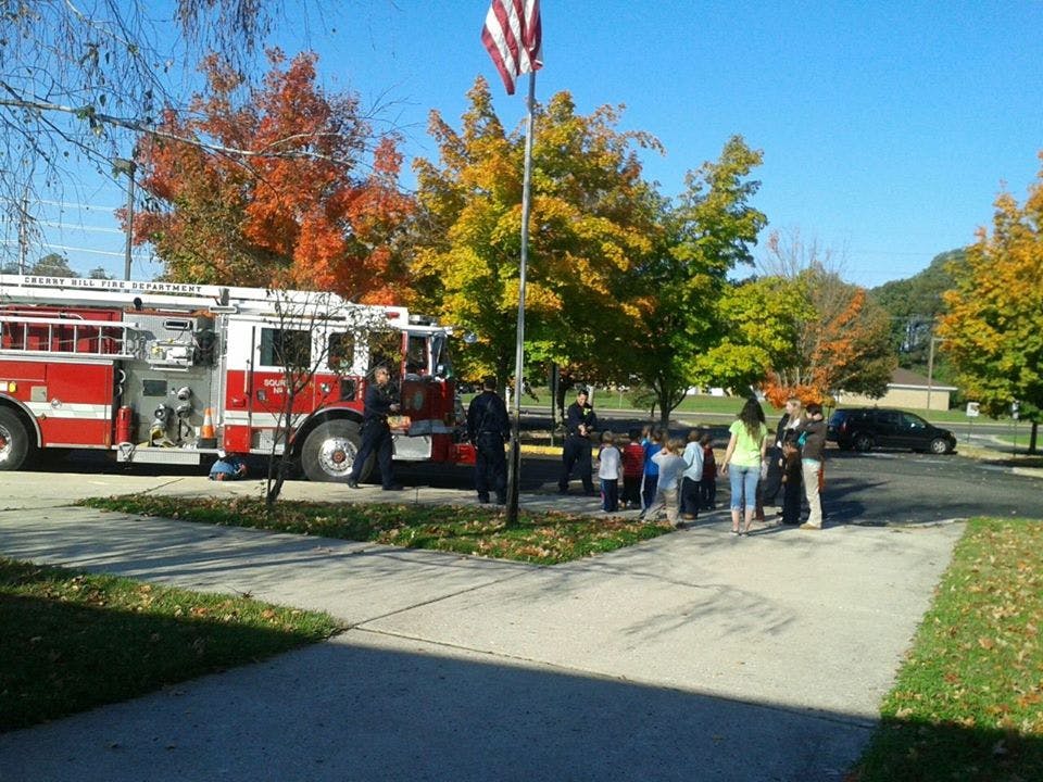 Fire truck parked with adults and children standing nearby