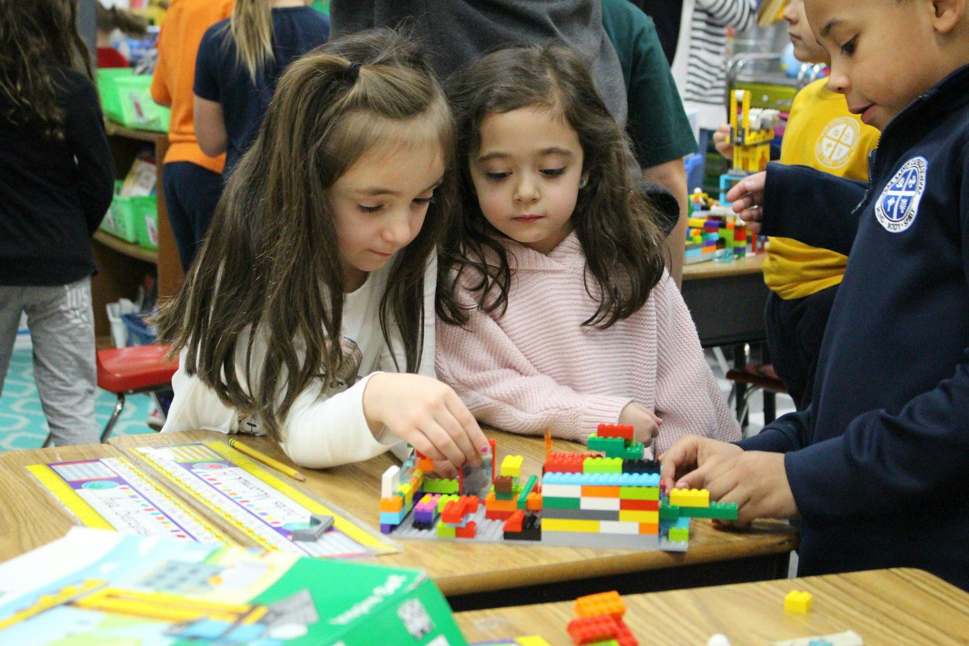 Three children building with colorful blocks at a table