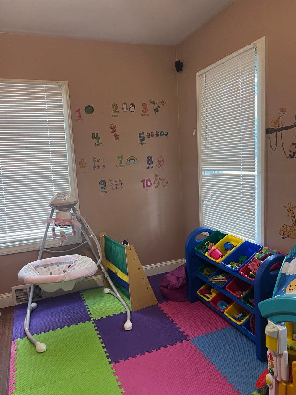 Playroom with baby swing, toy organizer, and number decals on the wall