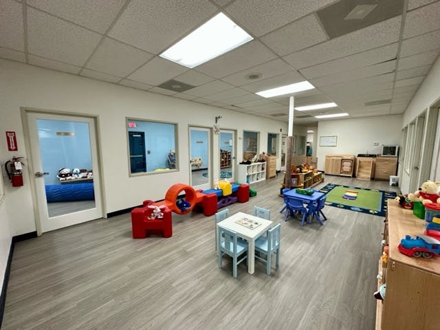 Playroom with small tables and chairs, soft play equipment, and open doorways