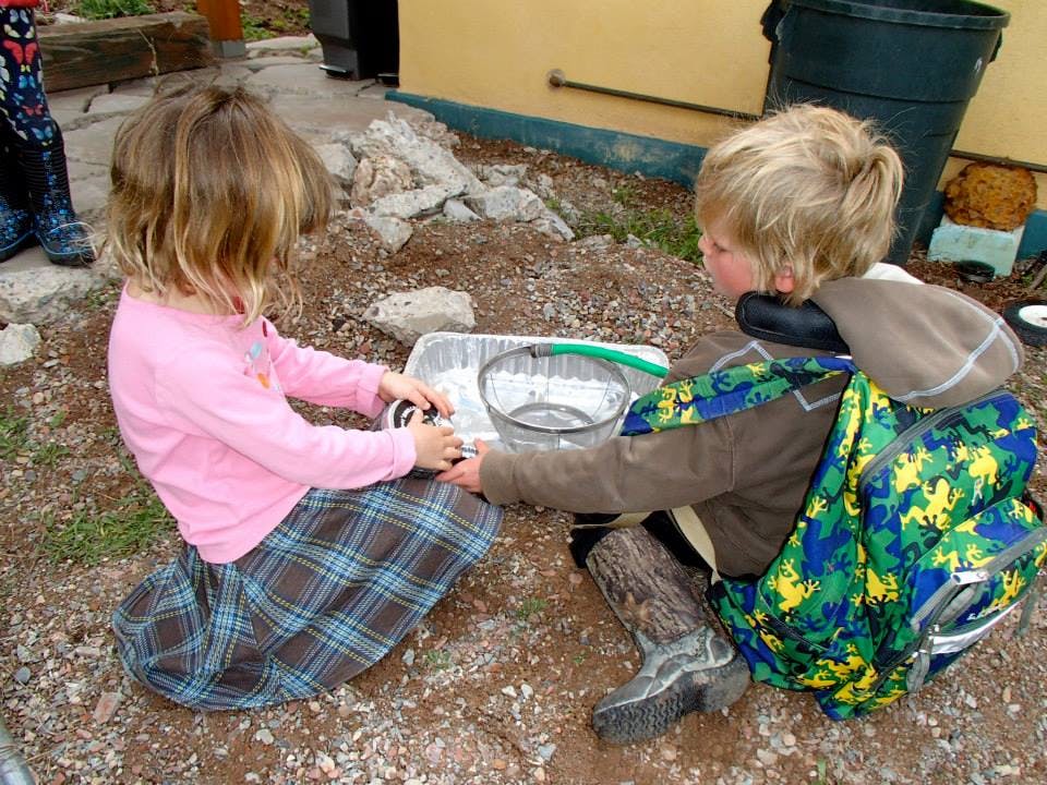 Two children playing with bowls on the ground